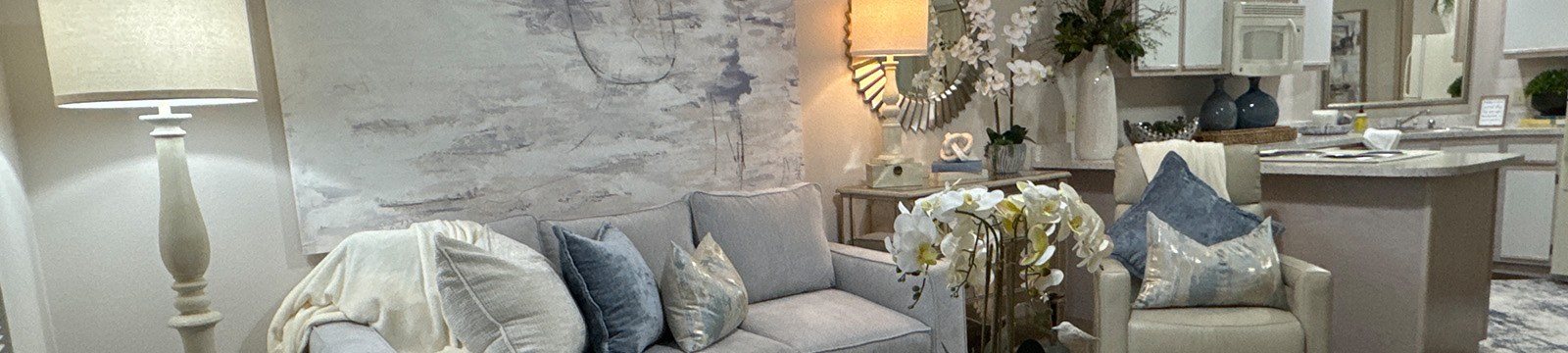 A living room with a grey couch and a white floor lamp.